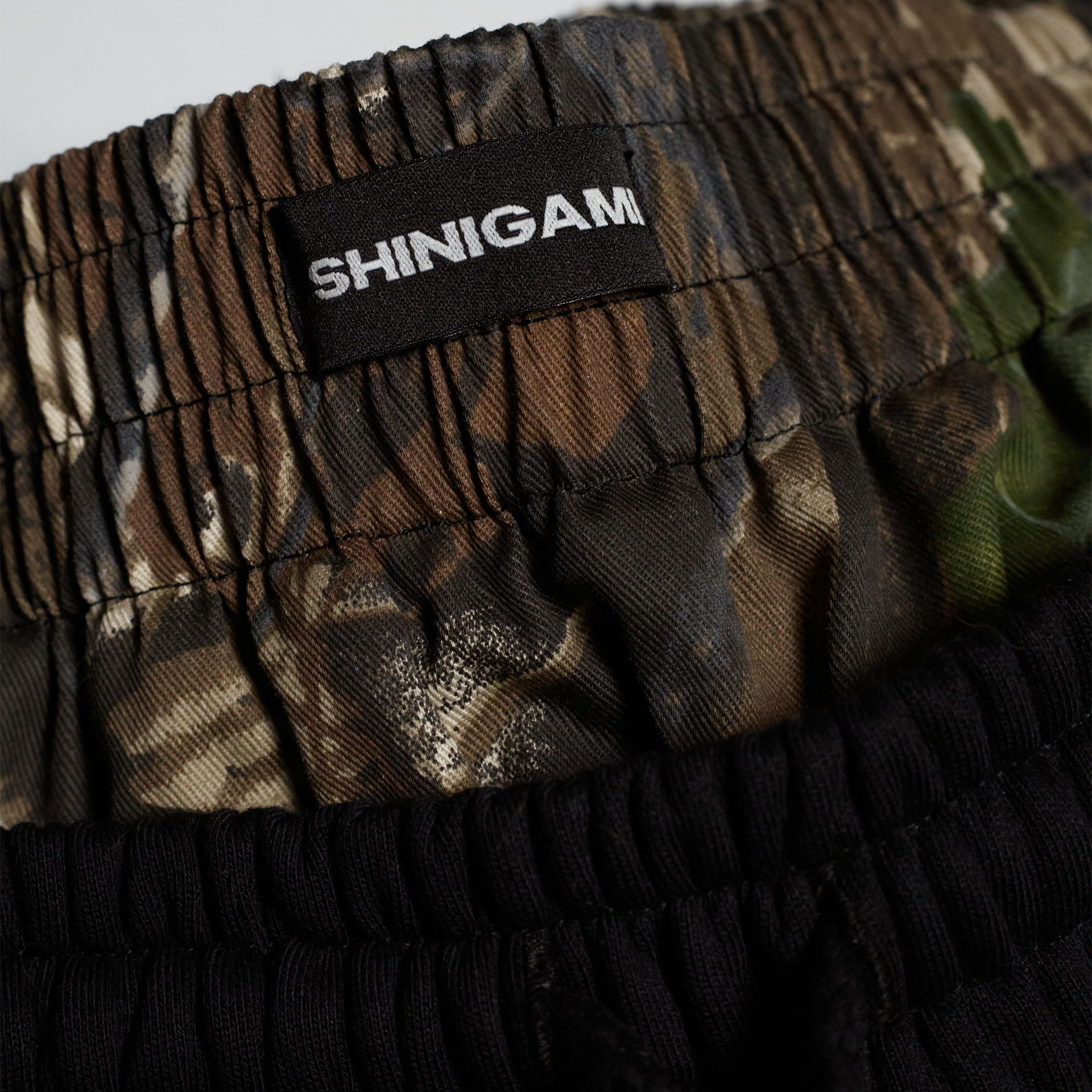 Shinigami Couture black shorts camouflage waistband with branded label detail