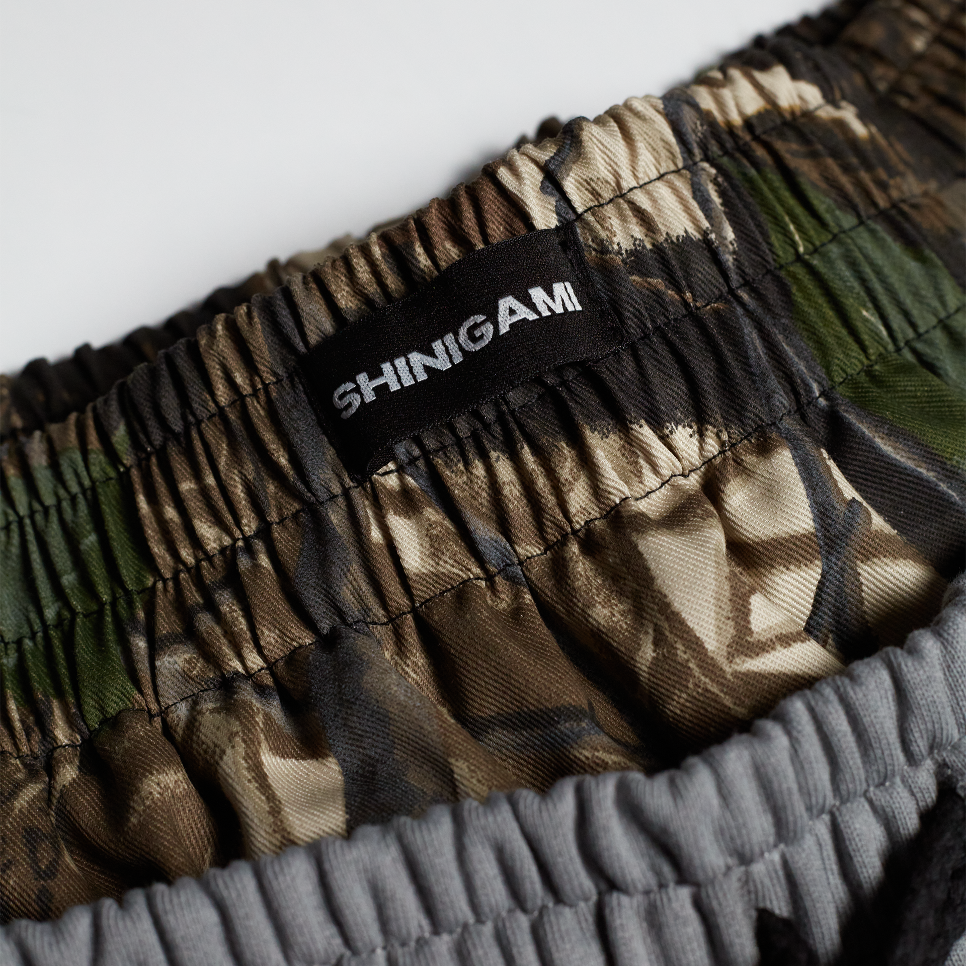 Shinigami Couture light gray shorts camouflage waistband with branded label detail